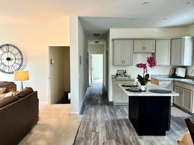 kitchen with gray cabinets, a kitchen island, dark wood-type flooring, and sink