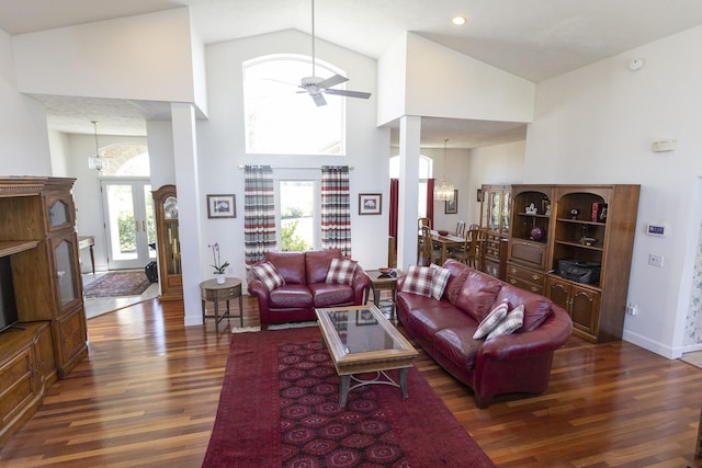 living room featuring dark hardwood / wood-style floors, ceiling fan with notable chandelier, and high vaulted ceiling