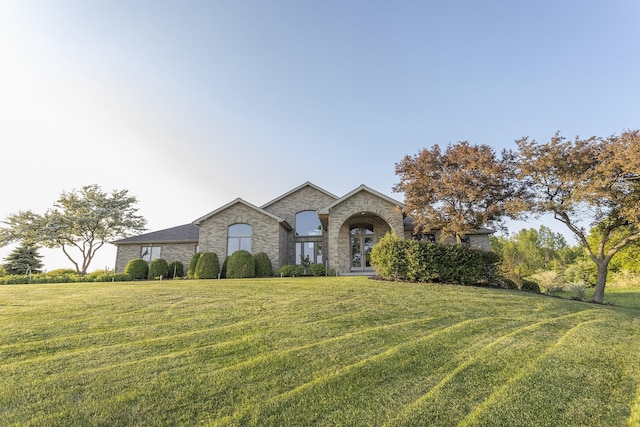 french country inspired facade featuring a front yard and french doors