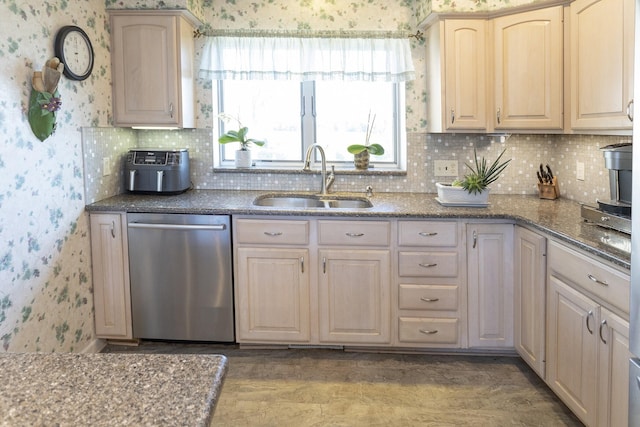 kitchen featuring backsplash, dishwasher, light stone countertops, and sink