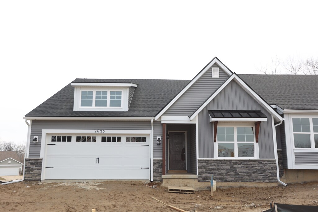 1025 Camellia Cir Unit 41, Howell, MI 48843 - craftsman-style home featuring stone siding, board and batten siding, a garage, driveway, and a shingled roof