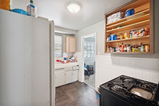 kitchen featuring white refrigerator, black range with gas stovetop, and light brown cabinetry