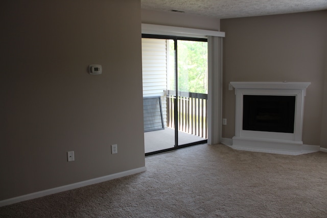 unfurnished living room featuring carpet and a textured ceiling