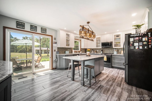 kitchen with white cabinetry, a center island, hanging light fixtures, stainless steel appliances, and gray cabinets