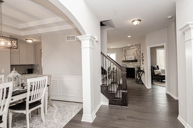 interior space featuring decorative columns, a fireplace, hardwood / wood-style floors, and a healthy amount of sunlight