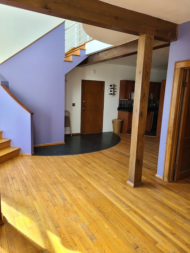 unfurnished living room with beam ceiling and light hardwood / wood-style floors