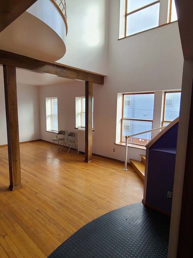 677 Selden St, Detroit, MI 48201 - unfurnished living room featuring light wood-style floors, radiator heating unit, a towering ceiling, and stairway