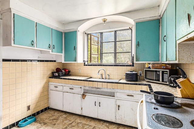 kitchen with sink, stove, and tile walls