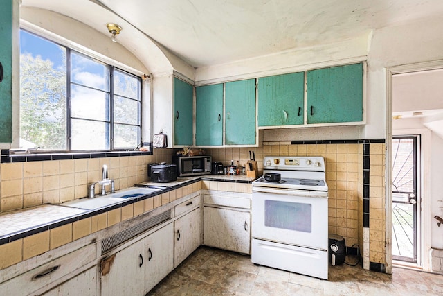 kitchen featuring white cabinetry, electric range, sink, tile counters, and tile walls