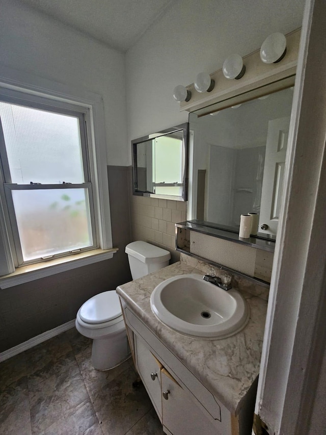 bathroom with vanity, toilet, and tile walls