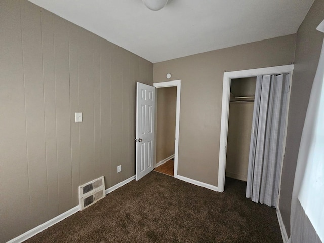 unfurnished bedroom featuring dark carpet and a closet