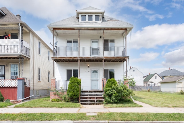 view of front of home with a balcony and a front lawn