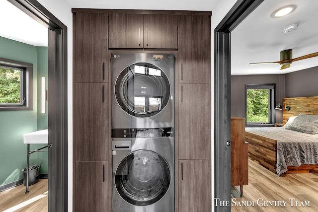 washroom with stacked washer / dryer, plenty of natural light, cabinets, and light wood-type flooring