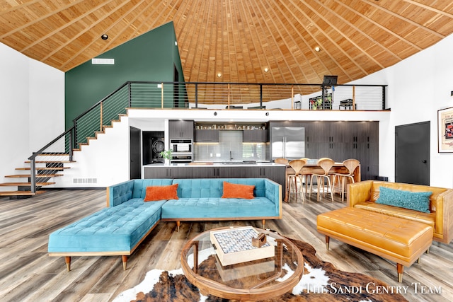 living room featuring hardwood / wood-style floors, high vaulted ceiling, wooden ceiling, and sink