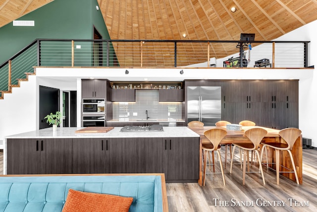 kitchen with wood ceiling, dark brown cabinetry, stainless steel appliances, and light hardwood / wood-style floors