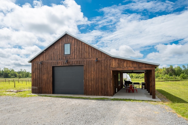 garage featuring a rural view and a yard