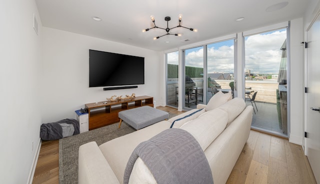 living room with a chandelier, light wood-type flooring, and floor to ceiling windows