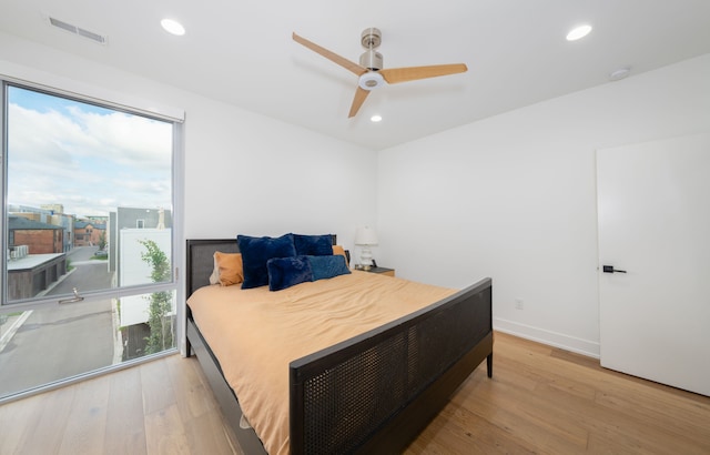 bedroom with ceiling fan, light hardwood / wood-style flooring, and multiple windows