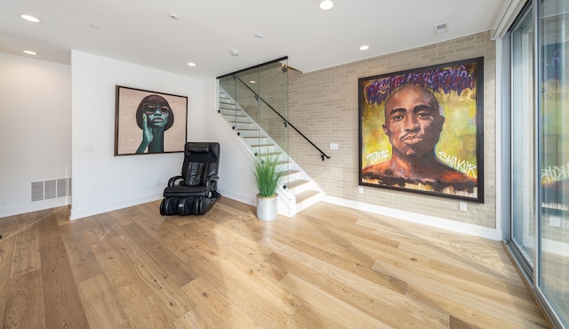 living room with hardwood / wood-style floors and brick wall