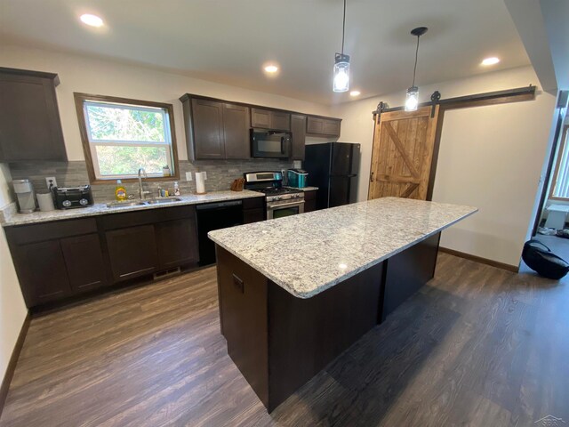 kitchen with decorative backsplash, sink, black appliances, a barn door, and decorative light fixtures