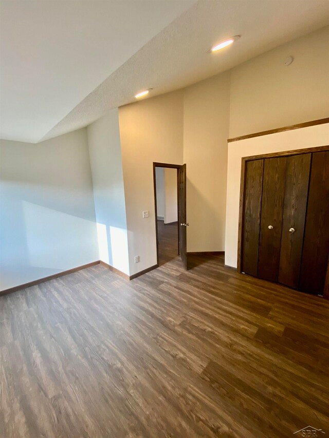 unfurnished bedroom featuring a textured ceiling, dark hardwood / wood-style flooring, and a closet