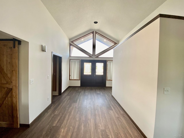 entrance foyer featuring dark hardwood / wood-style floors, a barn door, a textured ceiling, and high vaulted ceiling