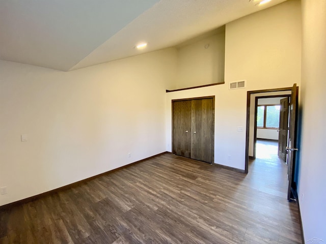3879 Kochville Rd, Saginaw, MI 48604 - unfurnished bedroom featuring dark wood-style flooring, baseboards, a closet, and high vaulted ceiling