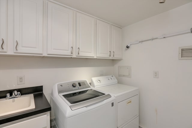 laundry area with cabinets, washing machine and dryer, and sink