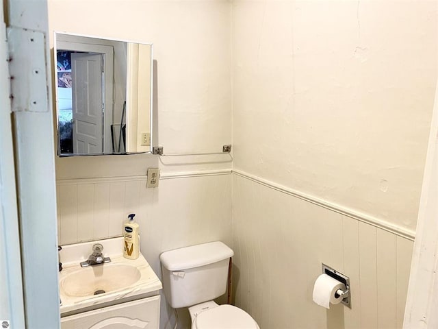 628 S Oak St, Mount Pleasant, MI 48858 - bathroom featuring vanity, toilet, wainscoting, and a decorative wall