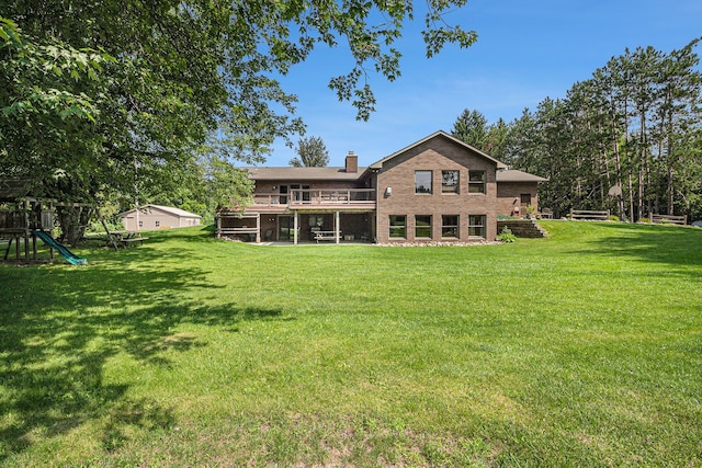 back of house featuring a lawn and a playground