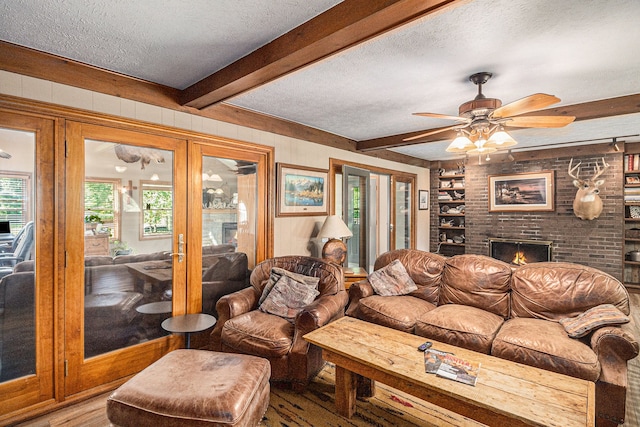 living room with hardwood / wood-style floors, ceiling fan, a textured ceiling, and a brick fireplace