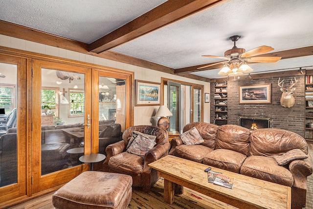 10133 W Allen Rd, Fowlerville, MI 48836 - living room with a textured ceiling, a fireplace, beamed ceiling, ceiling fan, and wood finished floors