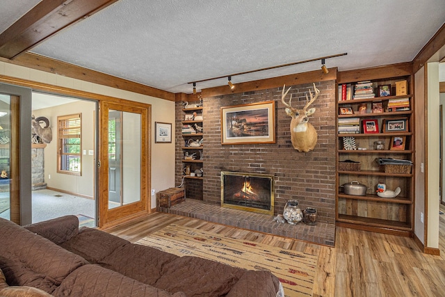 living room featuring light hardwood / wood-style floors, a textured ceiling, and a brick fireplace