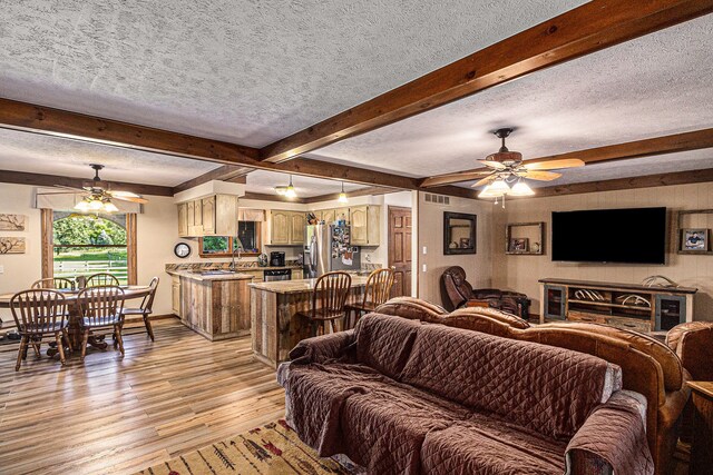 10133 W Allen Rd, Fowlerville, MI 48836 - living room with a ceiling fan, light wood-style flooring, a textured ceiling, beamed ceiling, and baseboards