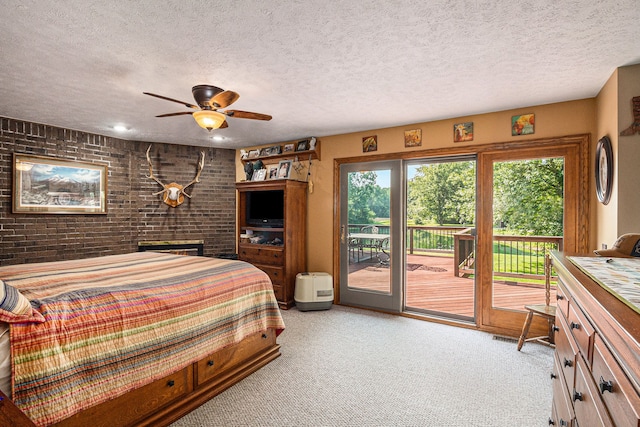 carpeted bedroom featuring access to exterior, a textured ceiling, ceiling fan, and brick wall