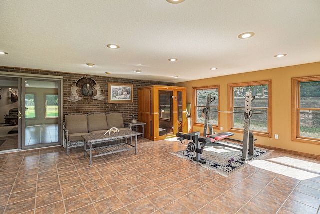 exercise room with tile patterned flooring, a textured ceiling, and brick wall