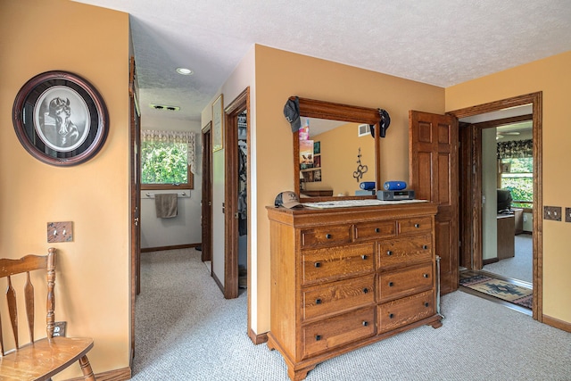 hall featuring light carpet and a textured ceiling