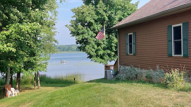 view of home's exterior with a lawn, central AC unit, and a water view