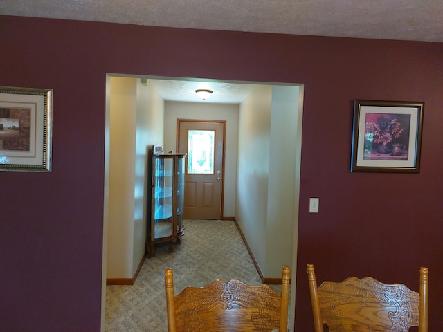 corridor featuring light colored carpet and a textured ceiling