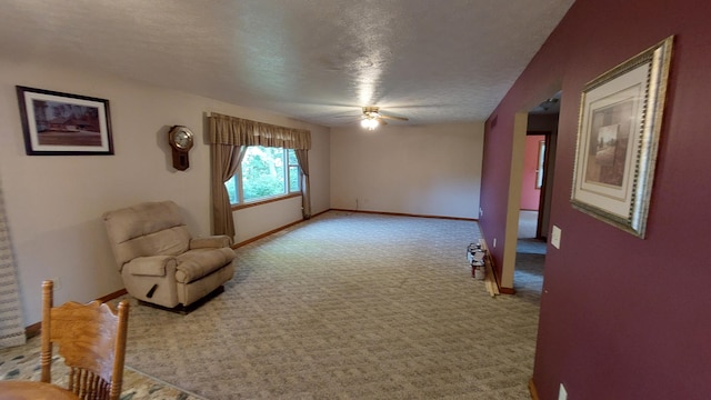 sitting room with ceiling fan, light colored carpet, and a textured ceiling