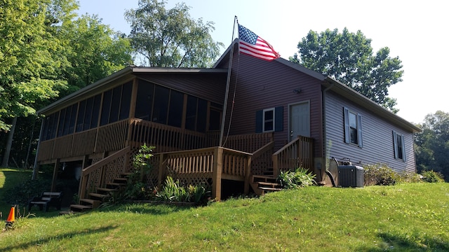 rear view of property with a sunroom, cooling unit, and a yard