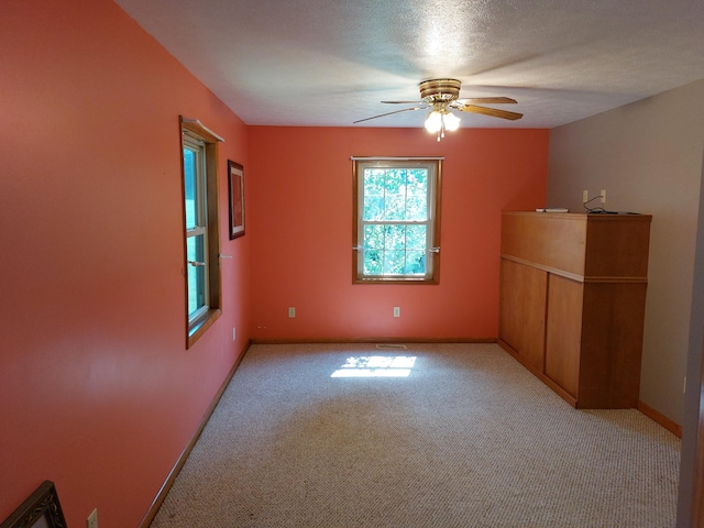 empty room with light carpet, a textured ceiling, and ceiling fan