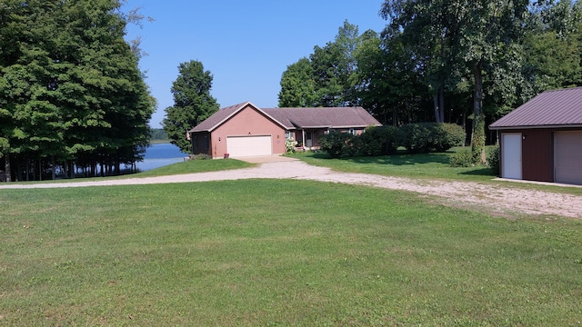 ranch-style home with a front lawn, a water view, and a garage