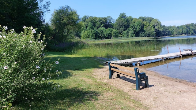 view of dock with a lawn and a water view