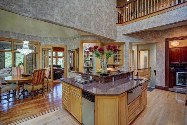 kitchen featuring pendant lighting, a high ceiling, sink, light hardwood / wood-style flooring, and dark stone countertops