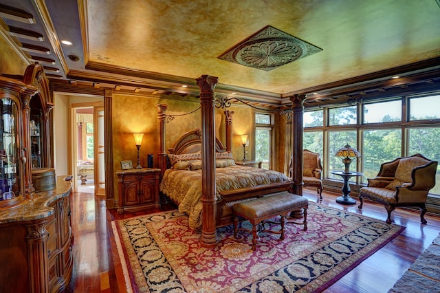 bedroom featuring decorative columns, wood-type flooring, and ornamental molding