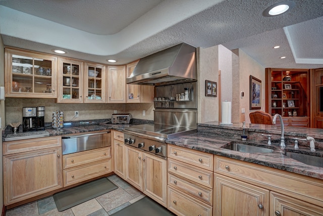 kitchen featuring a textured ceiling, sink, wall chimney range hood, and stainless steel gas stovetop