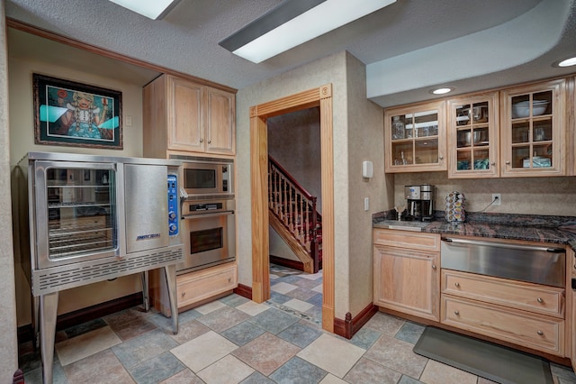 kitchen featuring light brown cabinets, wine cooler, dark stone countertops, a textured ceiling, and appliances with stainless steel finishes