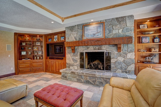 living room with built in shelves, a stone fireplace, and a textured ceiling