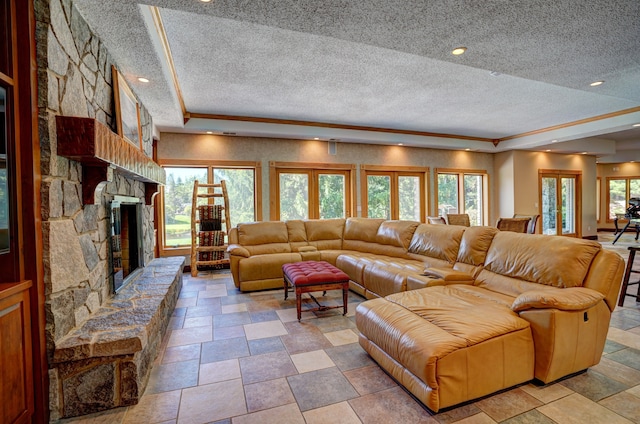 living room with a raised ceiling, a stone fireplace, and a textured ceiling